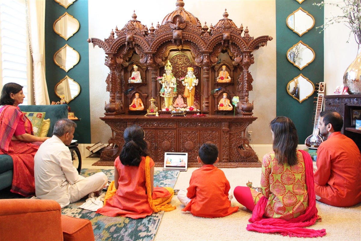 A family performs puja in front of their mandir at home